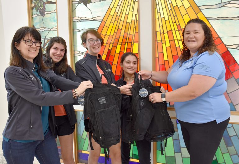 Robotics team holding community reach backpacks