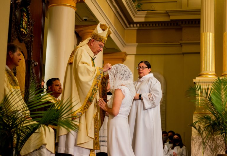 Archbishop Gregory Aymond moves the veil covering Claire Gallagher's head at her consecration.